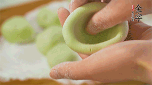 將均分的艾草面團搓成圓，挖一個窩，放入餡心，再搓成圓。