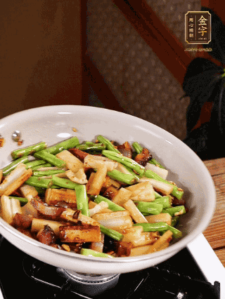 油熱下蒜末、干辣椒、醬肉煸炒出香味，依次下藕條、豆角翻炒均勻